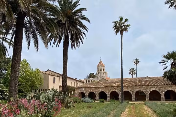 Stone arched monastery building with bell tower and palm trees on Saint-Honorat Island, French Riviera