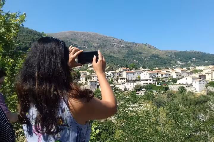 Tourist photographing hilltop village of Saint-Paul-de-Vence with smartphone on sunny day