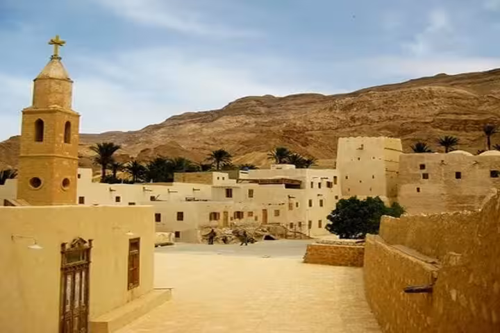 Saint Paul Monastery courtyard near Hurghada, Coptic church tower and desert mountains on full-day tour