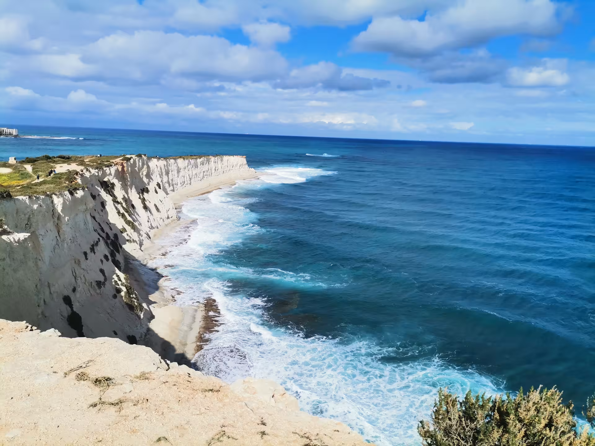 White limestone sea cliffs above turquoise water on Saint Pauls Bay coastal hike with local picnic in Malta