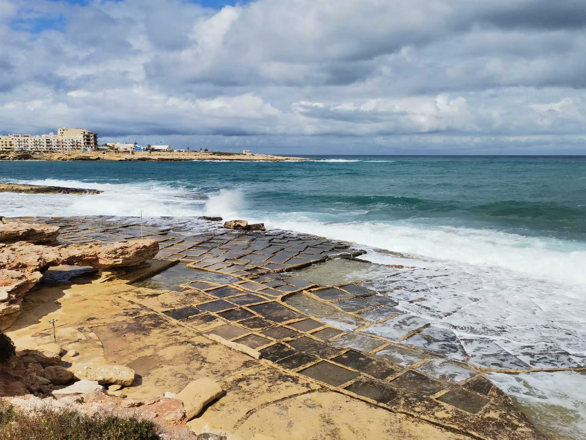 Waves crashing by Malta salt pans near Saint Pauls Bay on a guided coastal hike, scenic route before local picnic