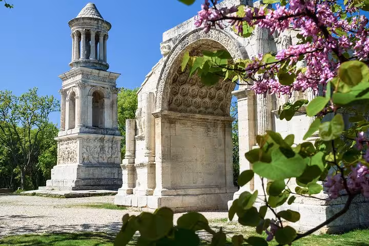 Explore the ancient Roman ruins in Saint Rémy, surrounded by vibrant spring blossoms and lush greenery.