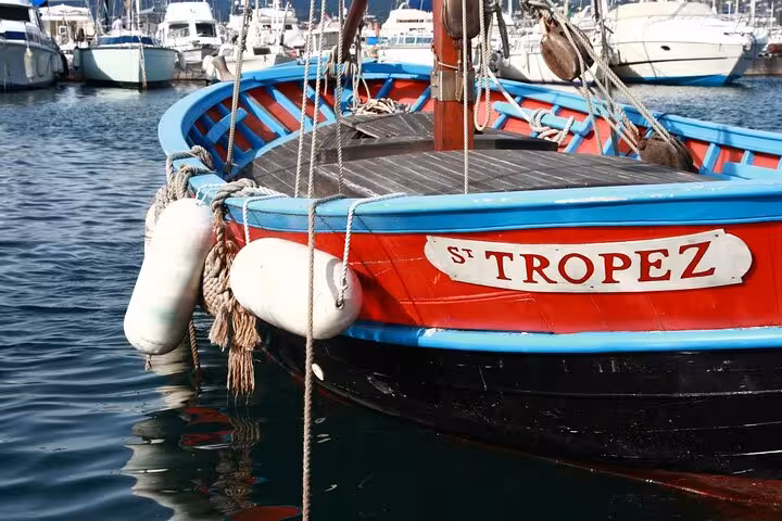 Colorful wooden boat named Saint-Tropez docked at marina with white fenders and ropes