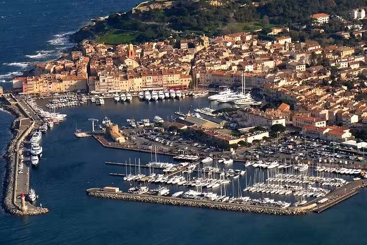Aerial view of Saint-Tropez harbor with yachts, marina, and colorful old town buildings along the French Riviera coastline