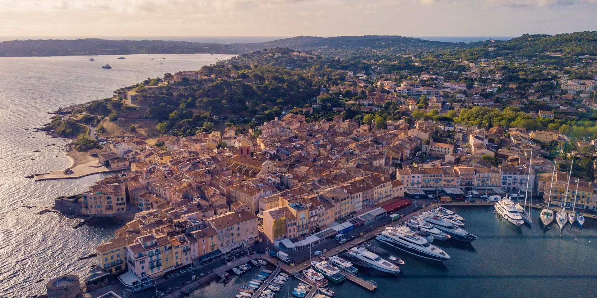 Aerial view of Saint-Tropez old town harbor with yachts and terracotta rooftops along the French Riviera coast