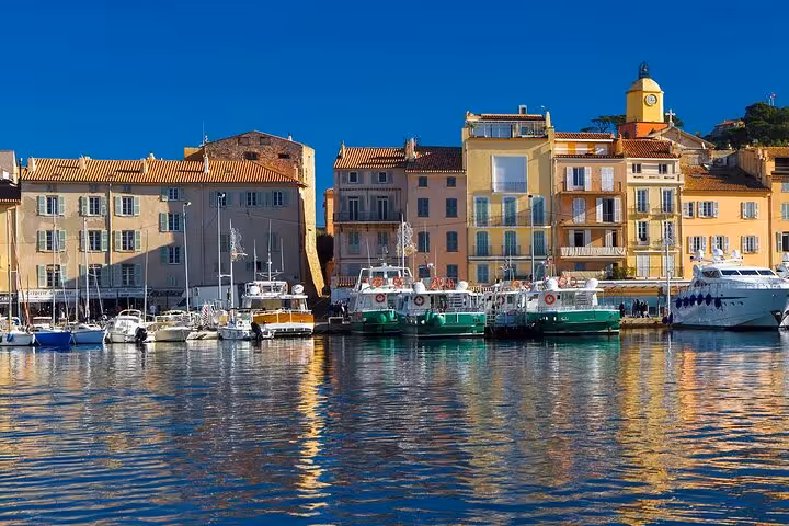 Colorful waterfront buildings and boats docked in Saint-Tropez harbor on a sunny day