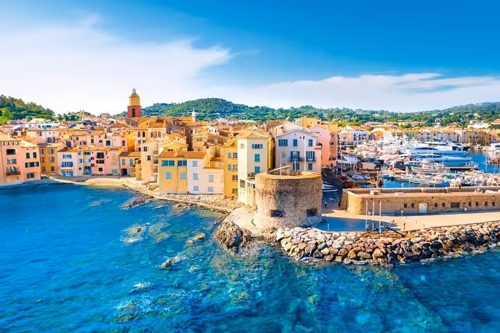 Colorful waterfront buildings and marina of Saint-Tropez with turquoise Mediterranean waters and hillside backdrop