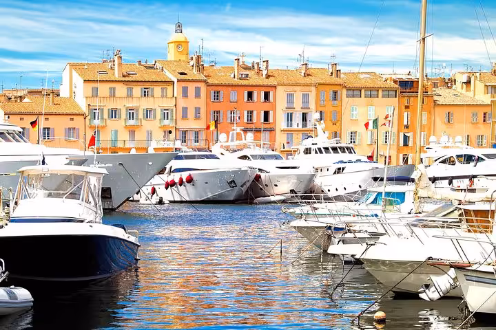 Colorful waterfront buildings and luxury yachts docked in Saint-Tropez harbor on a sunny day