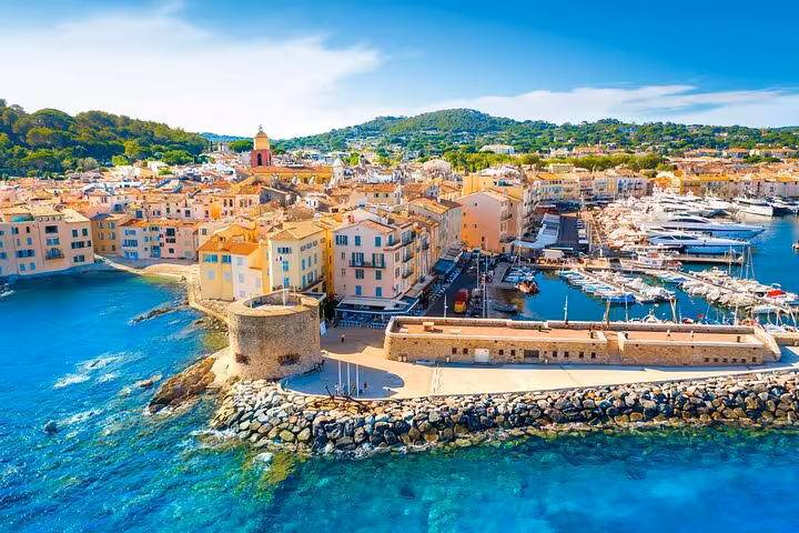 Aerial view of Saint-Tropez harbor with colorful buildings, marina with yachts, and turquoise Mediterranean water
