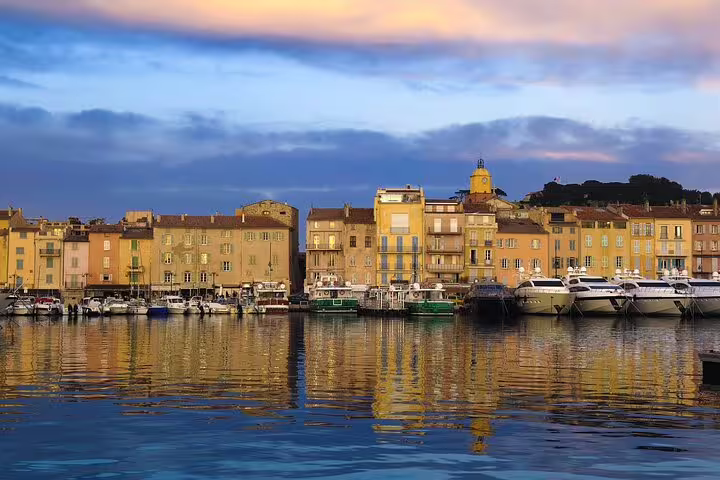 Colorful waterfront buildings and yachts reflected in the harbor of Saint-Tropez at sunset