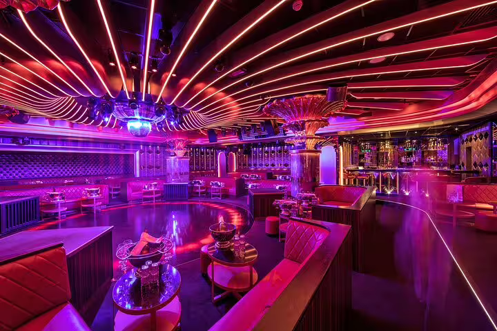 Luxurious nightclub interior with red and purple neon lights, dance floor, bar, and VIP seating areas