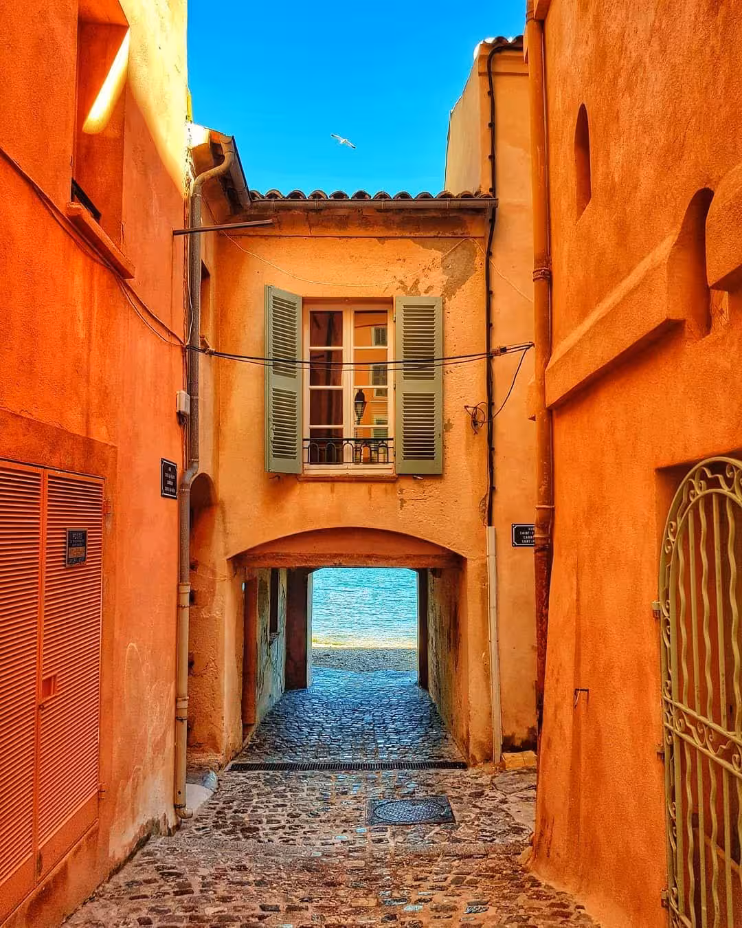 Narrow cobblestone alley with orange buildings and arched passageway in Saint-Tropez old town