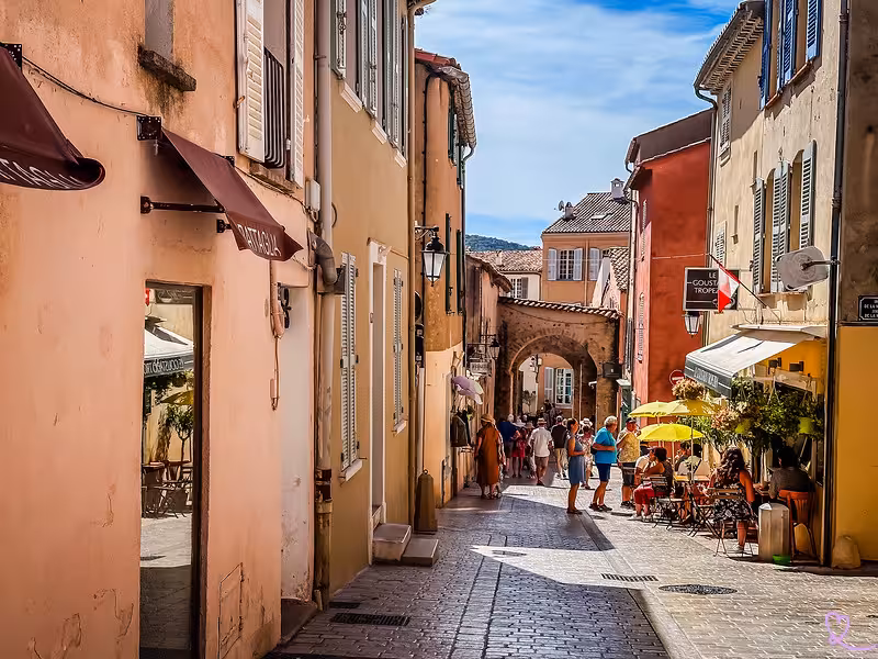 Cobblestone street lined with colorful buildings and outdoor café in Saint-Tropez old town