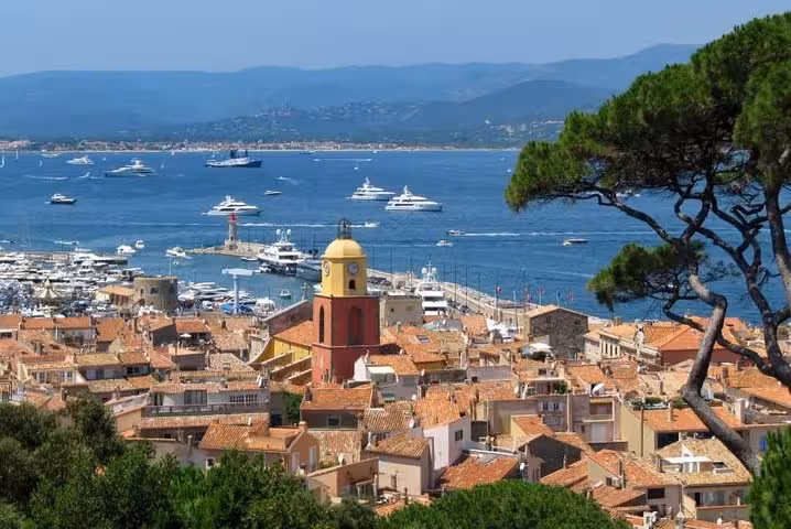 Aerial view of Saint-Tropez old town with iconic bell tower, terracotta rooftops, and yachts in the harbor