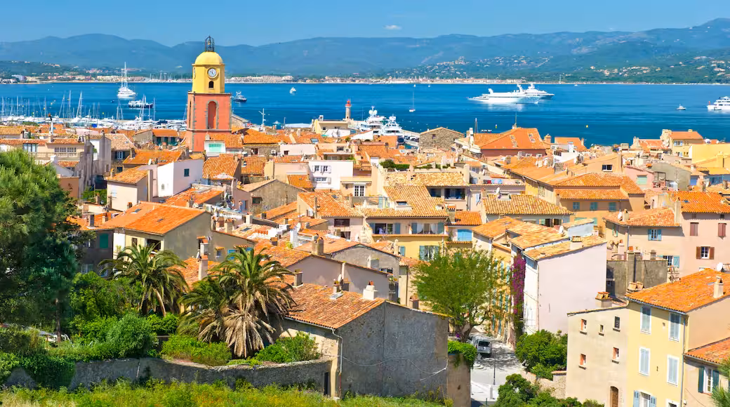 Aerial view of Saint-Tropez old town with orange rooftops, clock tower, and luxury yachts in the harbor