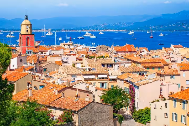 Panoramic view of Saint-Tropez old town with terracotta rooftops, clock tower, and yachts on the blue Mediterranean Sea