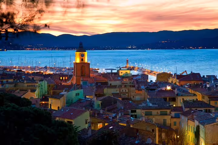 Saint-Tropez old town at sunset with illuminated church tower and harbor in the background