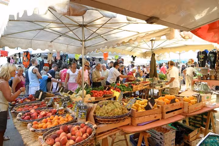 Colorful outdoor fruit and vegetable market stalls with crowds shopping in Saint-Tropez, France