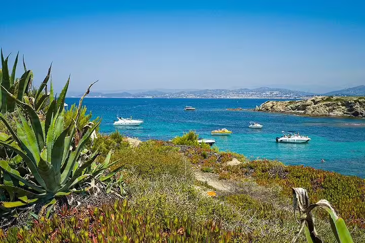 Turquoise Mediterranean cove with anchored yachts near Saint-Tropez, rocky coastline and agave plants in foreground