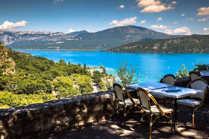 Outdoor terrace overlooking turquoise Sainte-Croix Lake with mountains and sailboats, Verdon Gorge, France
