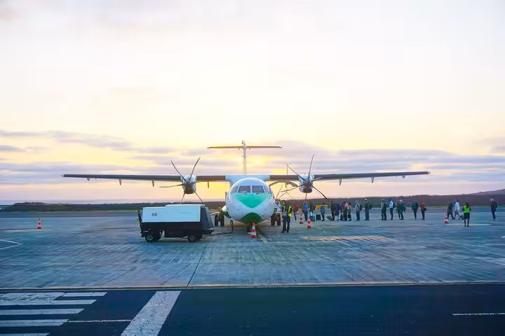 Passengers boarding a propeller aircraft at Sal Airport during sunset for a private transfer to Murdeira Cape Verde.