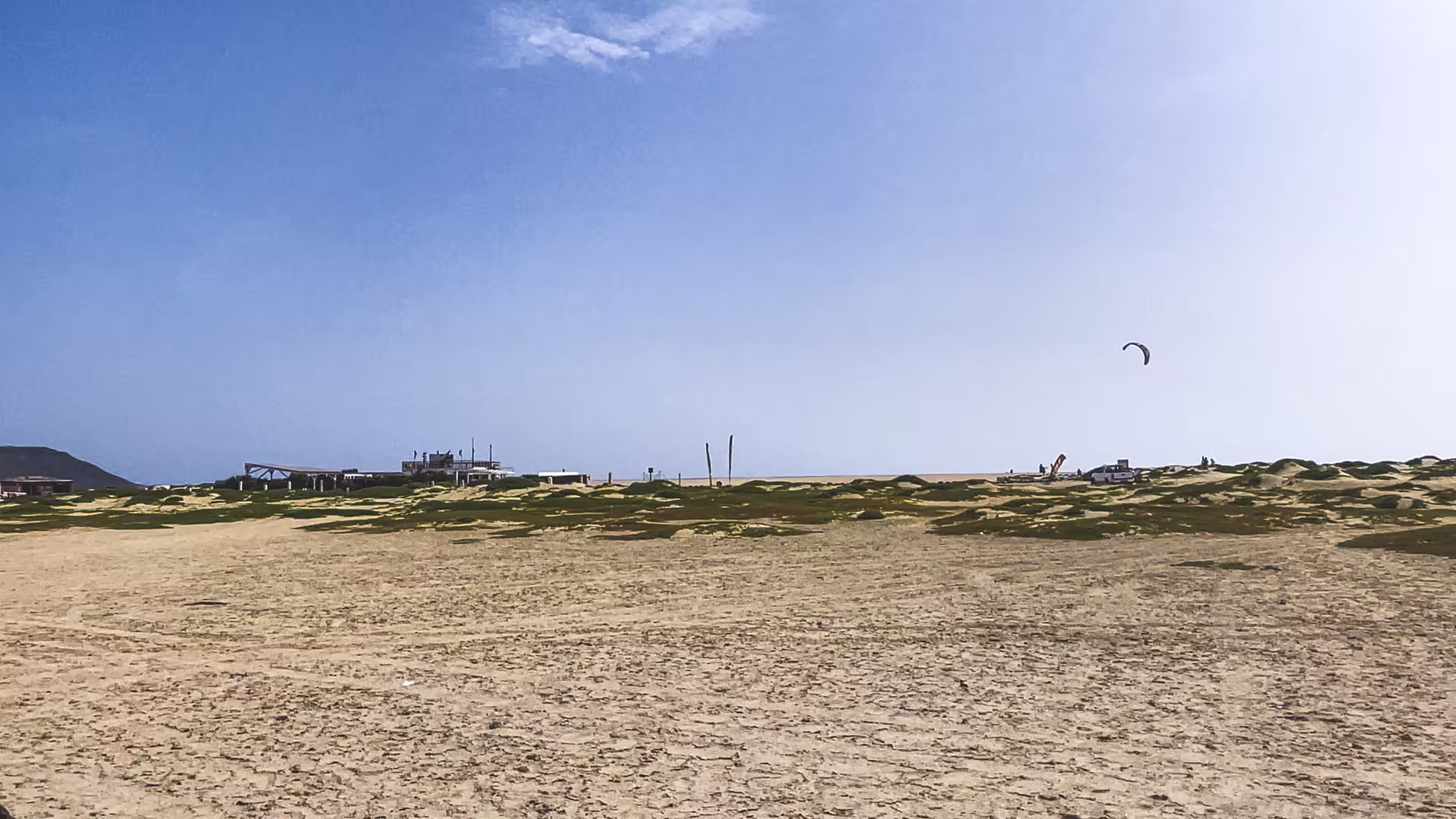 Wide sandy beach on Sal Island tour, Cape Verde, with dunes, beach bar and kitesurfing kite overhead