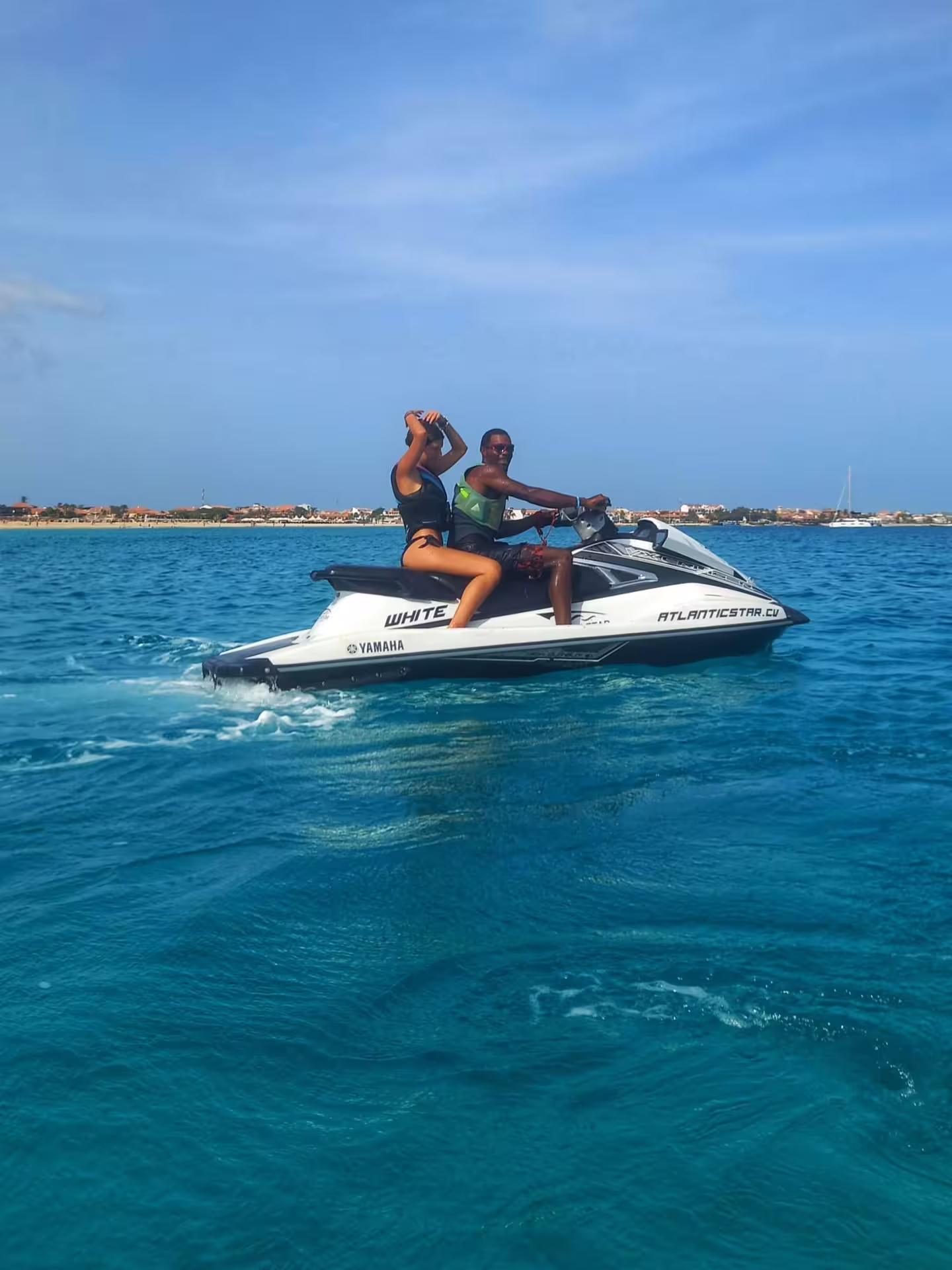Couple captures a moment on a jet ski, gliding over Sal Island's clear waters under a bright blue sky.