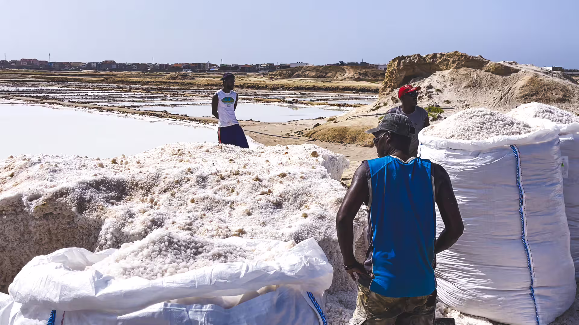 Salt workers and large salt piles at Pedra de Lume salinas, a highlight of Sal Island full-day tour