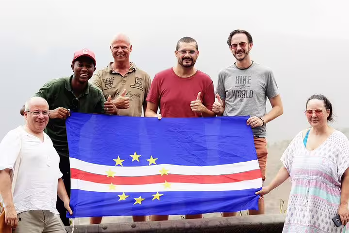 Happy group holding the Cape Verde flag on Sal Island viewpoint during a full-day private tour with local guide