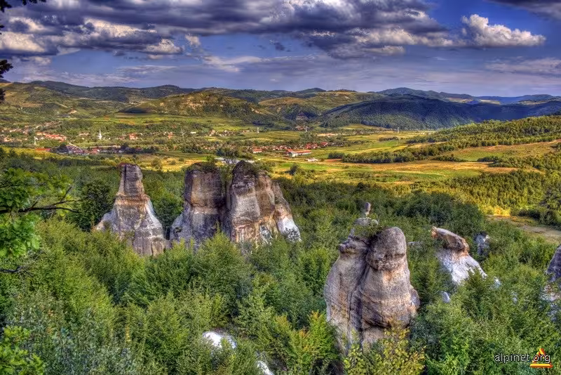 Dramatic rock formations surrounded by lush greenery with a scenic valley and village in Salaj, Romania