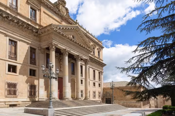 Neoclassical building with grand columns and steps in Salamanca, Spain under blue sky