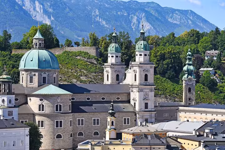 Salzburg Cathedral baroque domes and twin towers with green copper roofs and Alpine mountains backdrop