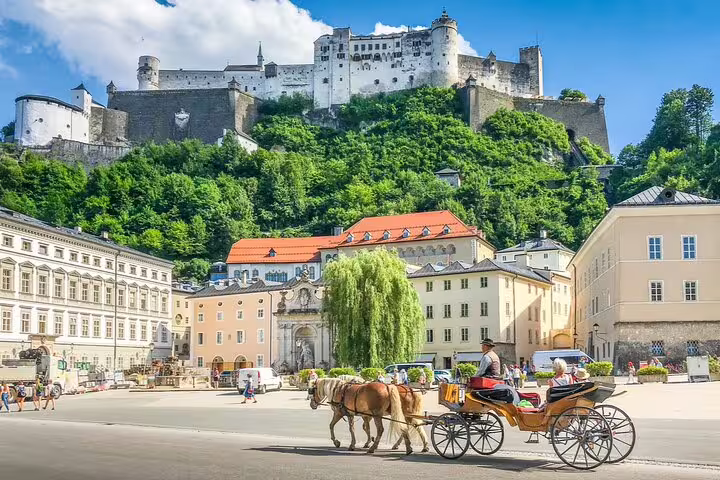 Horse-drawn carriage in Salzburg's old town square with Hohensalzburg Fortress on hilltop behind