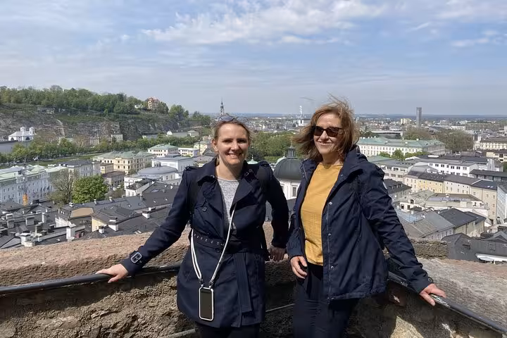 Two women smiling at a scenic overlook above Salzburg Old Town rooftops on a Mozart Mystery Walk