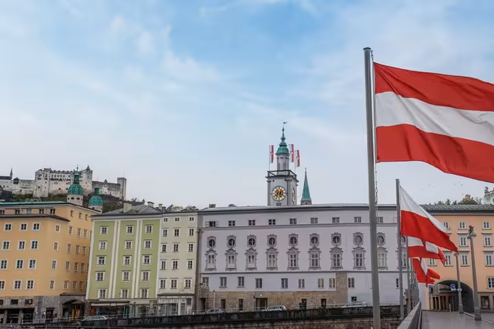 Austrian flags flying over Salzburg Old Town with Hohensalzburg Fortress and clock tower in background
