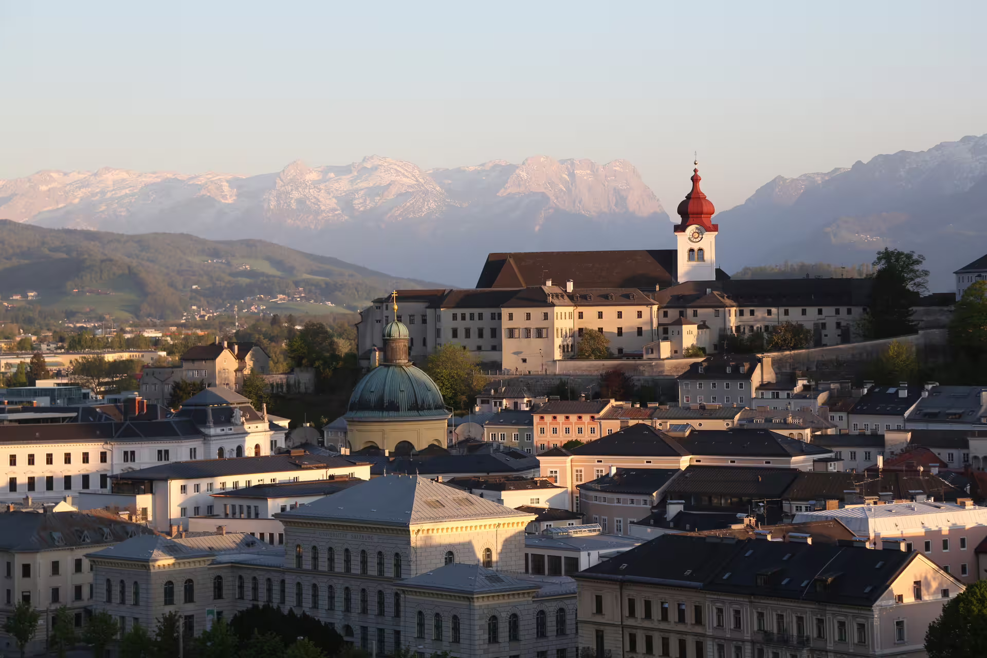 Panoramic view of Salzburg at sunset with historic architecture and the Alps, ideal for a Sound of Music city tour.