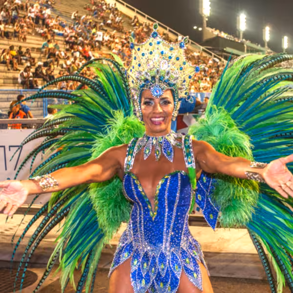Samba dancer in a dazzling blue and green costume performing energetically at a lively outdoor event.