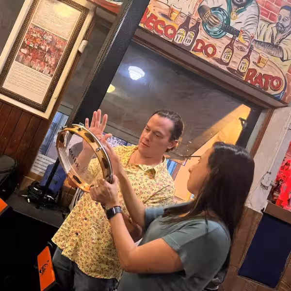 Man and woman learning to play a tambourine at a lively Samba Night Experience in Lapa, capturing cultural vibes.