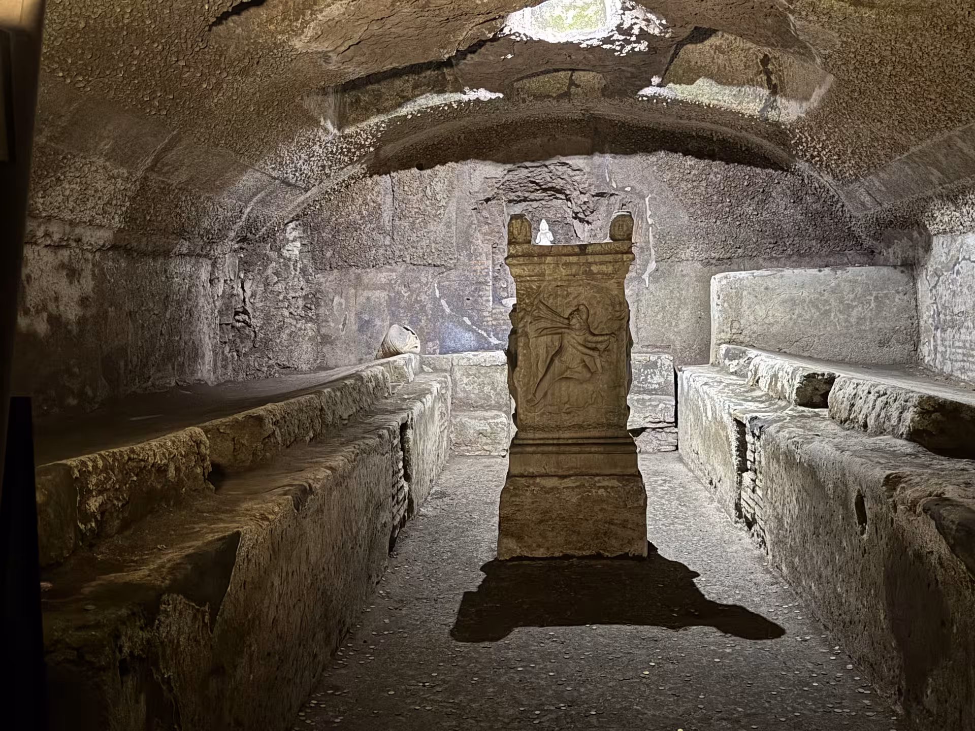 Ancient Mithraic temple beneath San Clemente Basilica in Rome, with stone altar and benches revealed on an underground ruins tour