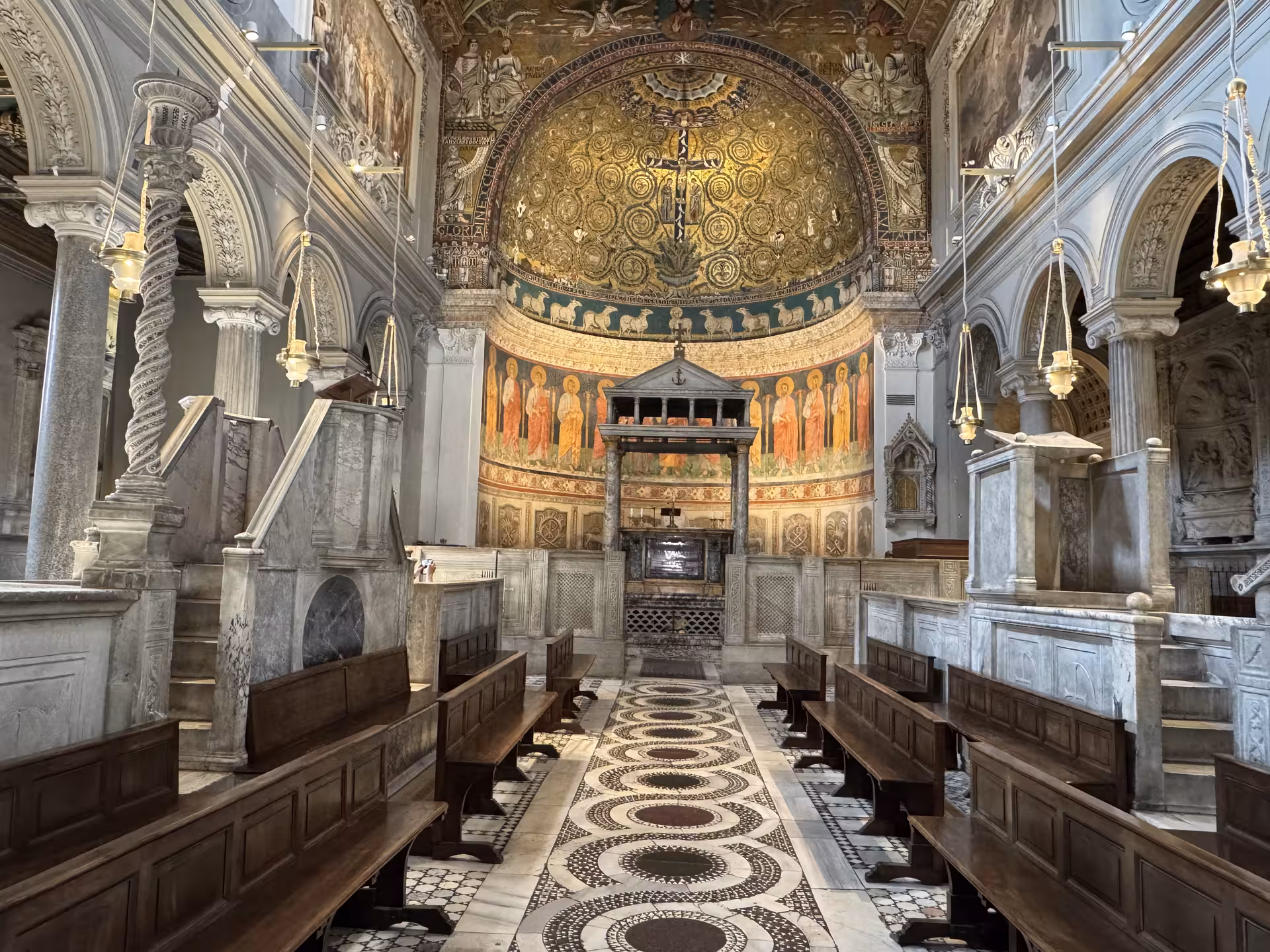 Ornate nave and golden apse mosaics of San Clemente Basilica in Rome, showcasing medieval Christian art and marble details