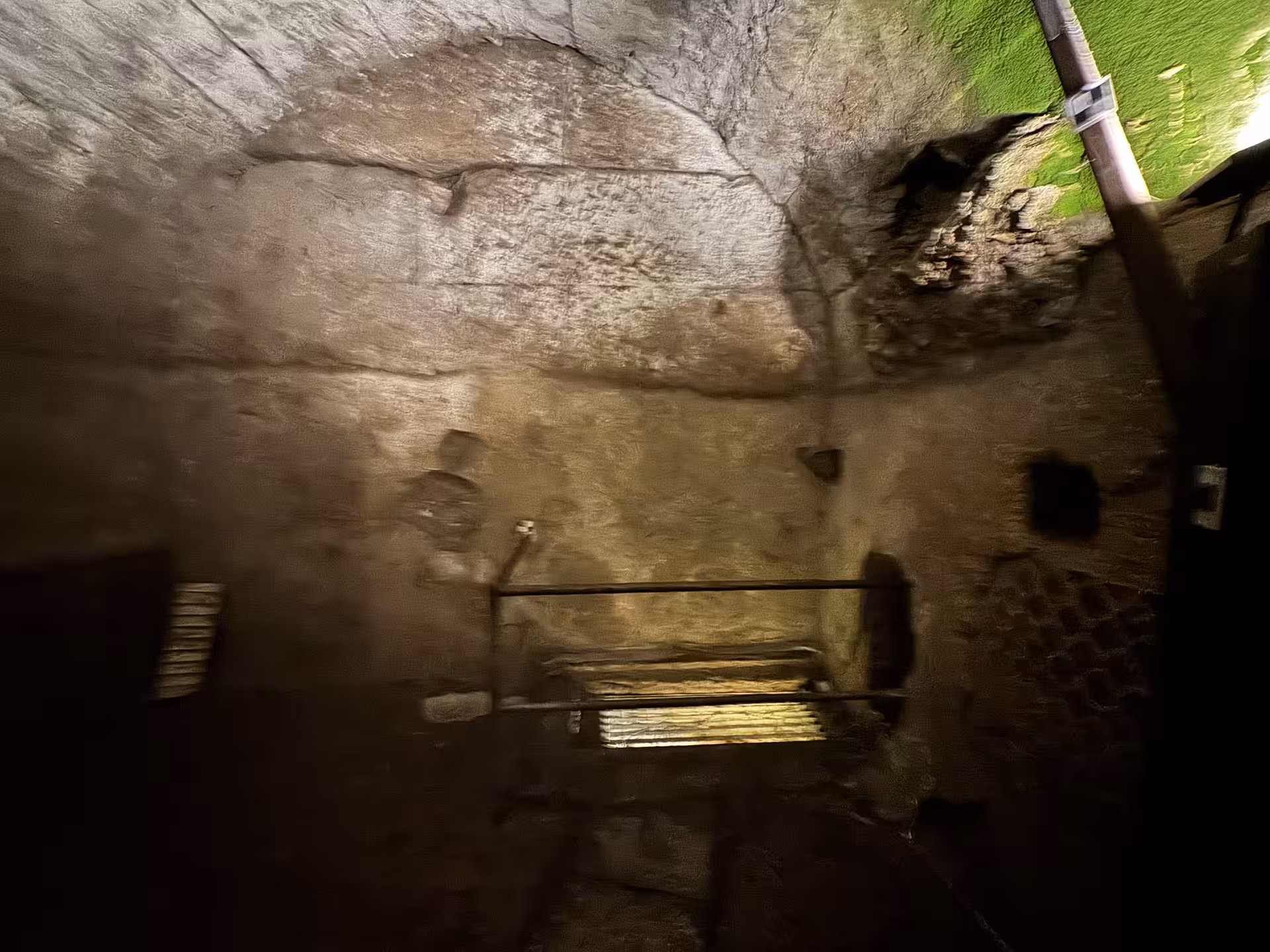Dimly lit underground chamber beneath San Clemente Basilica in Rome, revealing ancient stone walls and hidden archaeological ruins