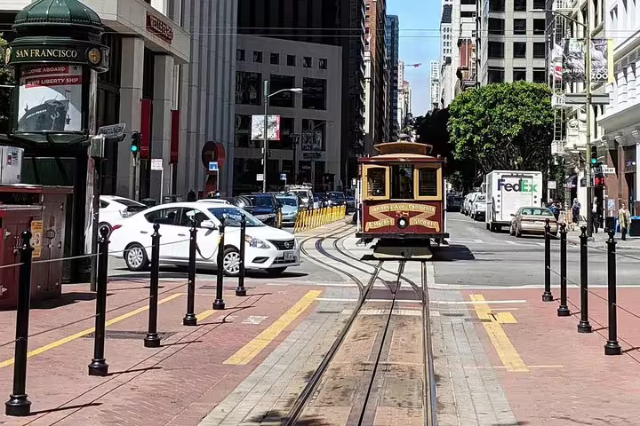 San Francisco cable car on Market Street tracks with historic buildings and city traffic