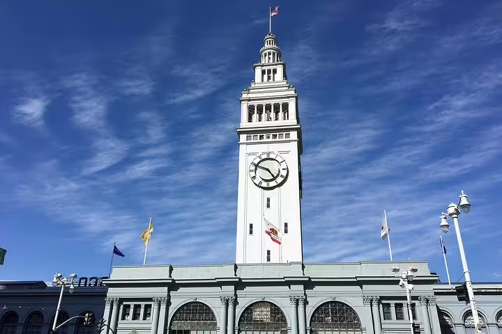 San Francisco Ferry Building clock tower with California state flag under blue sky