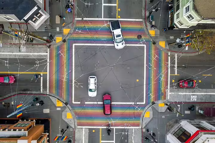 Aerial view of rainbow crosswalks at a San Francisco intersection with cars and pedestrians