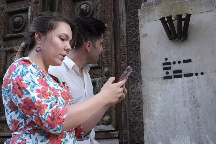 Two tourists solving puzzle clues on a self-guided walking quest near ornate historic building entrance