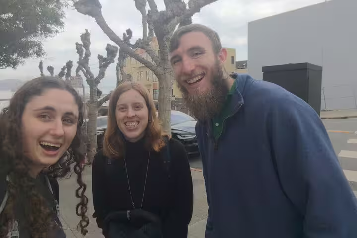 Three smiling friends on a street near Hyde Street Pier in San Francisco