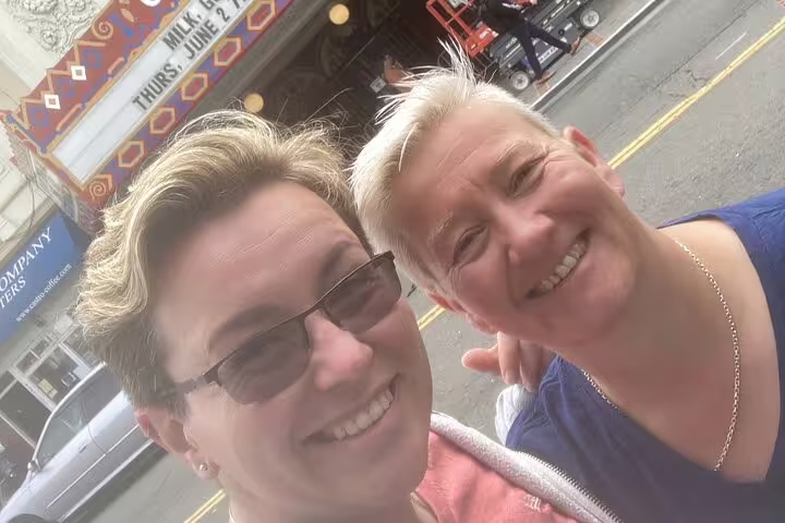 Two smiling people taking a selfie in front of a theater marquee in San Francisco