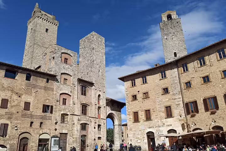 Historic stone towers and lively central square of San Gimignano visited on a Chianti Classic half-day Tuscany wine experience