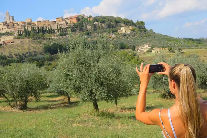 Traveler captures the scenic view of San Gimignano's rolling hills and olive groves in Tuscany on a sunny day.