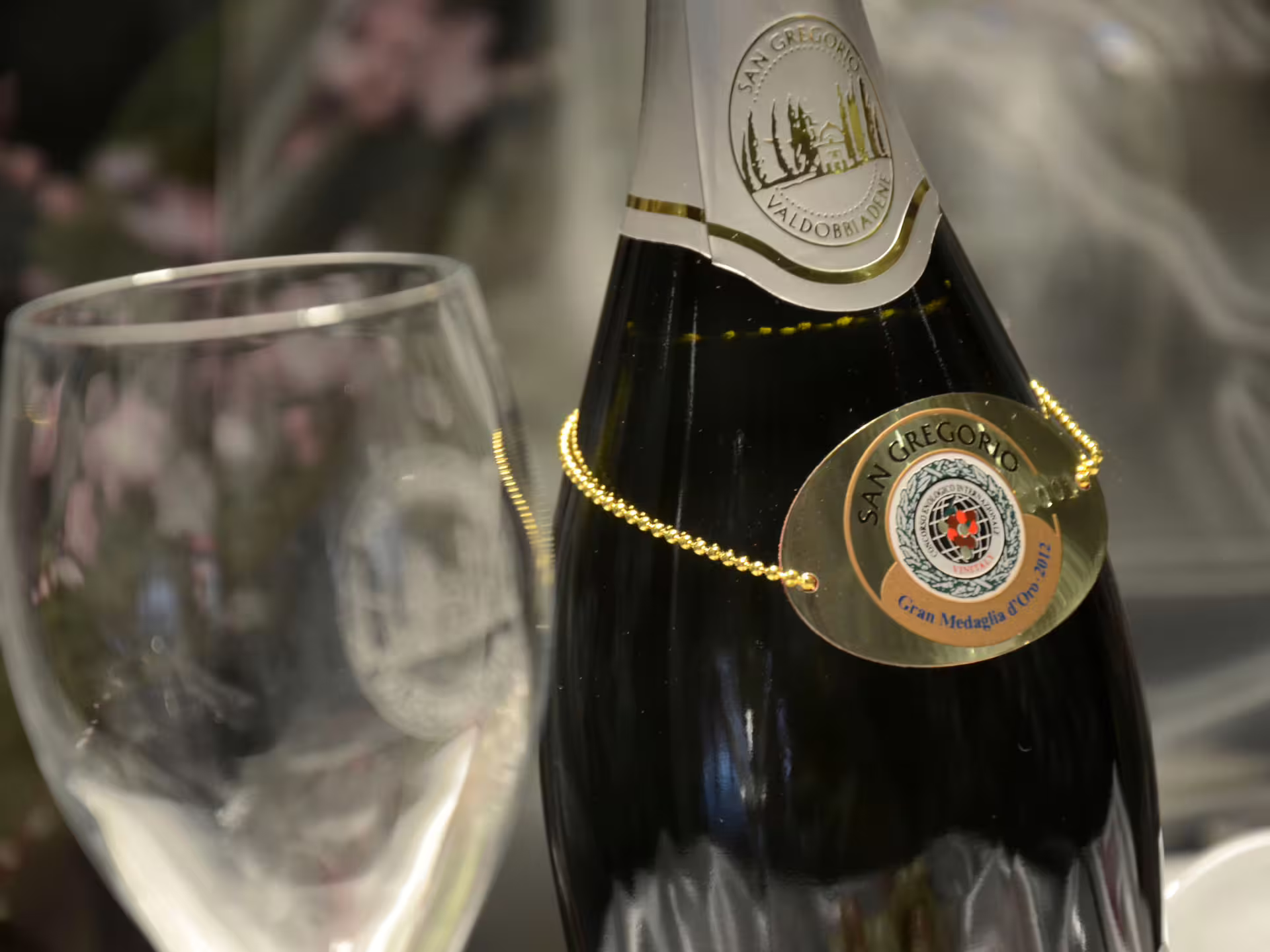 Close-up of a San Gregorio Prosecco bottle with gold medal award in a countryside winery setting.